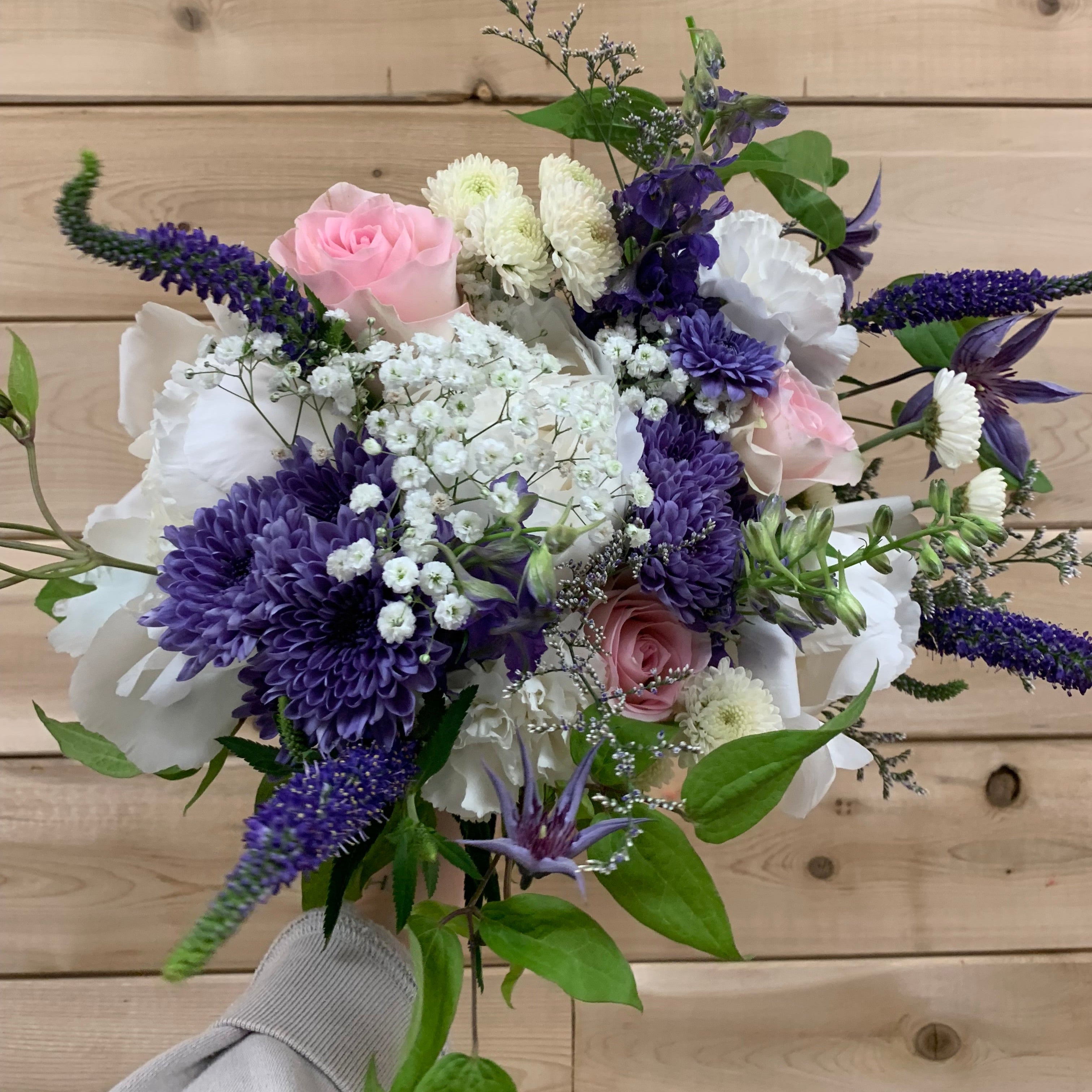 Bouquet of flowers with purple, white, and pink flowers against a wooden background